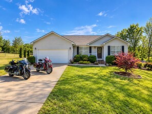 A two-story house with a garage, a driveway, and a well-maintained lawn. - Centerpoint Getaway - The Center of FUN in East TN! (Louisville)