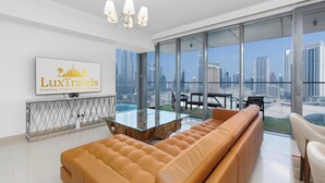 A modern living room with a glass coffee table, a leather sofa, and a city view through large windows. - Lux BnB Boulevard Point Burj Views (Dubai)