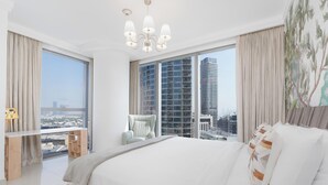 A modern hotel bedroom with a large bed, a view of a cityscape, and a balcony with a chair. - Lux BnB Boulevard Point Burj Views (Dubai)