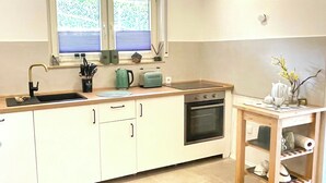 Eine Küche mit weißen Schränken, einem Spülbecken, einem Herd und einem Fenster mit Jalousien.