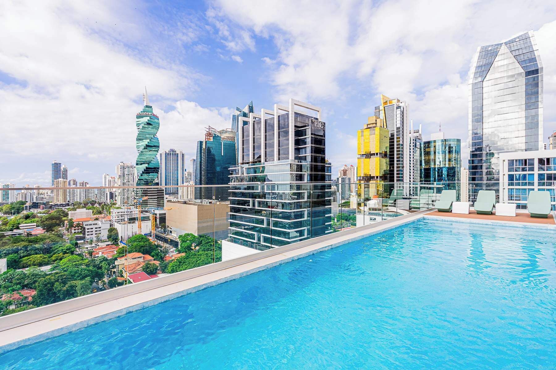 A modern hotel with a rooftop pool overlooking a cityscape.