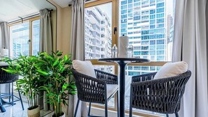 A modern room with a large window, two wicker chairs, a small round table, and a potted plant. - w Contemporary 1BR in Vibrant Obarrio (Panama City)