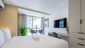 A hotel room with a bed, a desk, a chair, a TV, and a window with curtains. - w Contemporary 1BR in Vibrant Obarrio (Panama City)