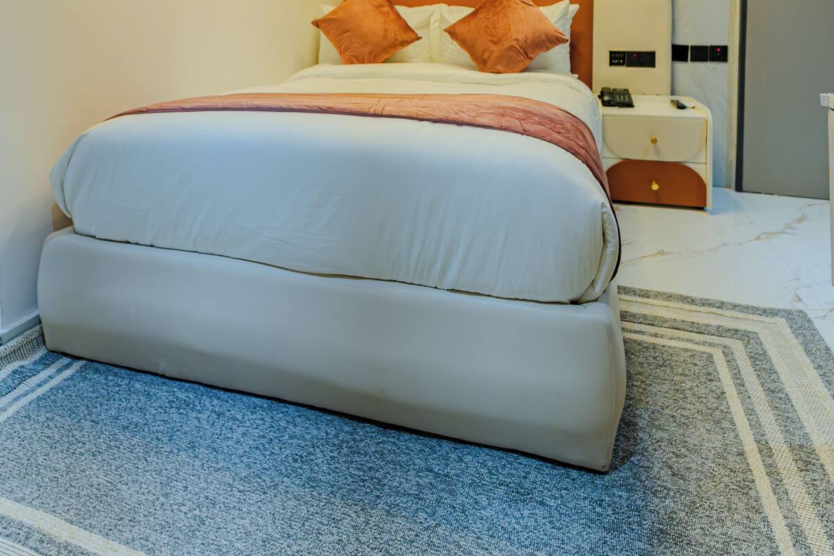 A modern bedroom with a large bed, a nightstand, a bedside table, and a circular light fixture on the ceiling.