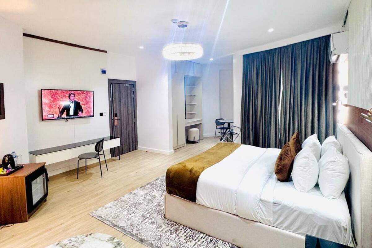 A modern hotel room with a bed, a desk, a TV, and a chair.