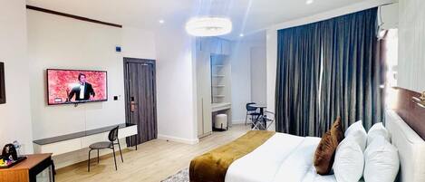 A modern hotel room with a bed, a desk, a TV, and a chair.