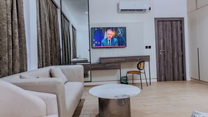 A modern living room with a sofa, a coffee table, a TV, and a wooden floor. - ATLANTIS HOTELS (Lagos)