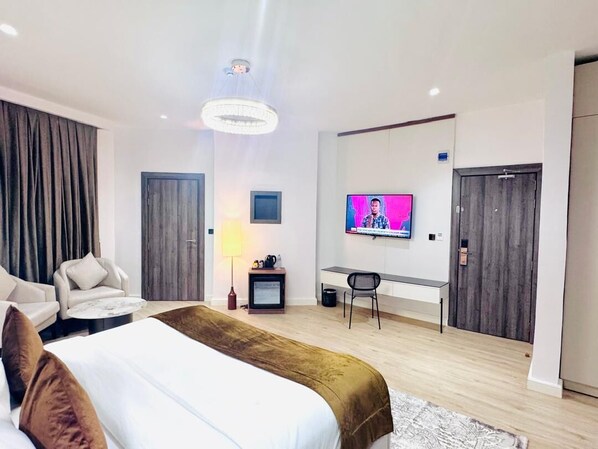 A modern hotel room with a large bed, a desk, a television, and a wardrobe. - ATLANTIS HOTELS (Lagos)