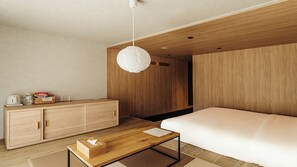 Habitació d'hotel moderna amb un llit de fusta, una petita taula de nit de fusta, escriptori i llum penjant.