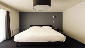 A modern hotel room with a large bed, a bedside table, a lamp, and a window with curtains. - LANSHAN HOTEL  (Naganuma)