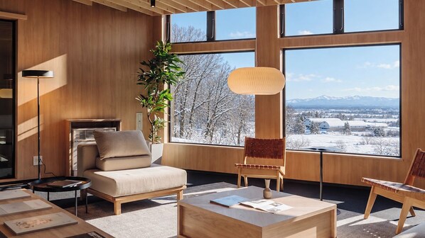 Ein modernes Wohnzimmer mit großem Fenster, einer Couch, einem Couchtisch und einem Sessel.