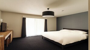 A hotel room with a bed, a desk with a computer, a lamp, and a window with curtains. - LANSHAN HOTEL  (Naganuma)