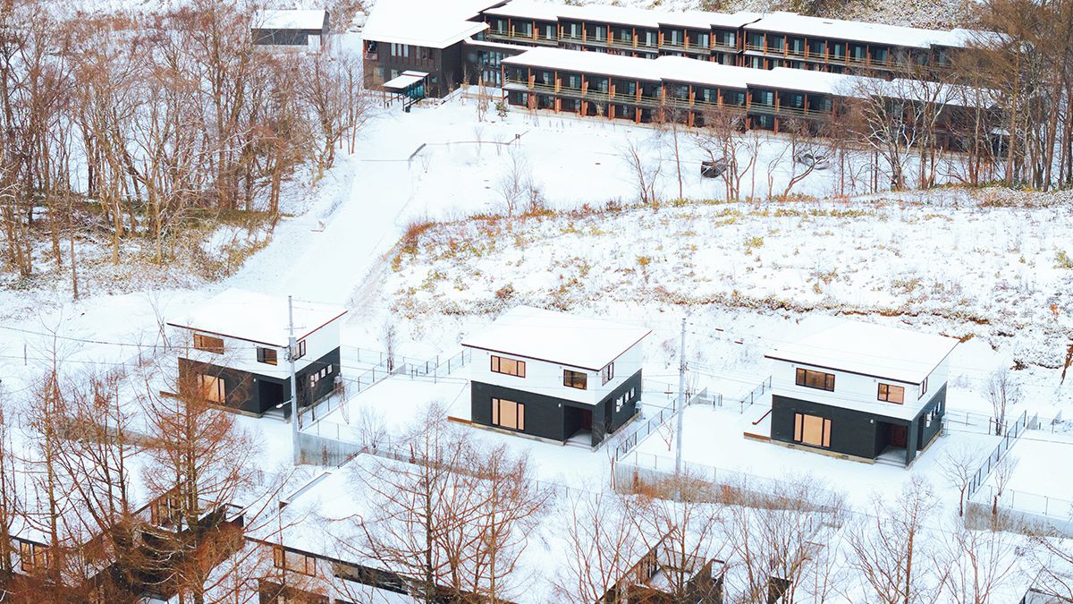 A modern building complex with multiple structures, including a central building with a flat roof and several smaller buildings with flat roofs, surrounded by a snowy landscape.