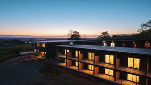 A modern multi-story building with large windows and a flat roof, surrounded by greenery and a view of the horizon. - LANSHAN HOTEL  (Naganuma)