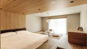 A modern hotel room with a wooden ceiling, a large bed, a small desk, and a window with blinds. - LANSHAN HOTEL  (Naganuma)