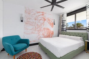 Une chambre à coucher moderne avec un lit vert, un fauteuil turquoise et un grand tableau abstrait accroché au mur.