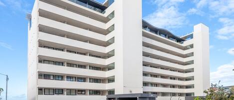Een meerlaags gebouw met een modern ontwerp, met balkons op elk verdiep en een hekwerkentree.