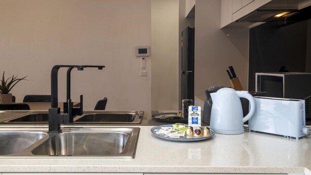 Eine moderne Küche mit Edelstahlspülen, einem Wasserkocher, einem Toaster und einem Teller mit Lebensmitteln.