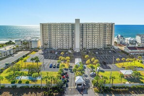 Ein großes Hotel mit mehreren Etagen, einem Parkplatz und Blick auf den Ozean.