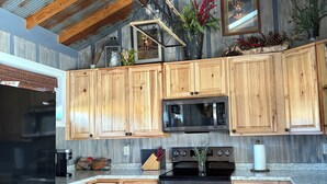 A kitchen with wooden cabinets, a stainless steel oven, and a black refrigerator.