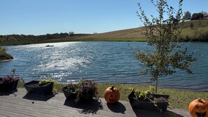 A wooden deck with potted plants and carved pumpkins by a lake.