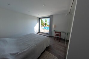 A bedroom with a large bed, a glass door leading to a balcony with a pool view. - Design villa, air-conditioned, heated swimming pool Marine de davia, corbara l'ile Rousse (Corbara)
