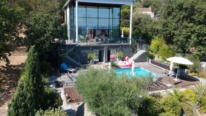 A modern house with a glass facade, a pool, and outdoor seating. - Design villa, air-conditioned, heated swimming pool Marine de davia, corbara l'ile Rousse (Corbara)