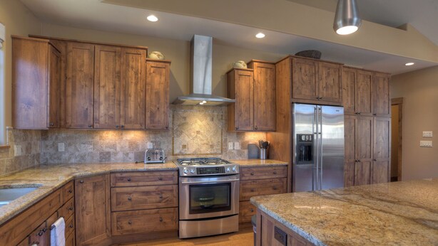 Una cocina con armarios de madera, un refrigerador de acero inoxidable, una estufa a gas y un horno.