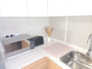 Departamento superior, vista al mar | Cocina privada | Refrigerador, microondas, horno y utensilios de cocina