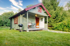 A small, single-story house with a porch, a grill, and a table with chairs. - Hus PIO – Your Lakeside Holiday Retreat in Southern Sweden (Traryd)