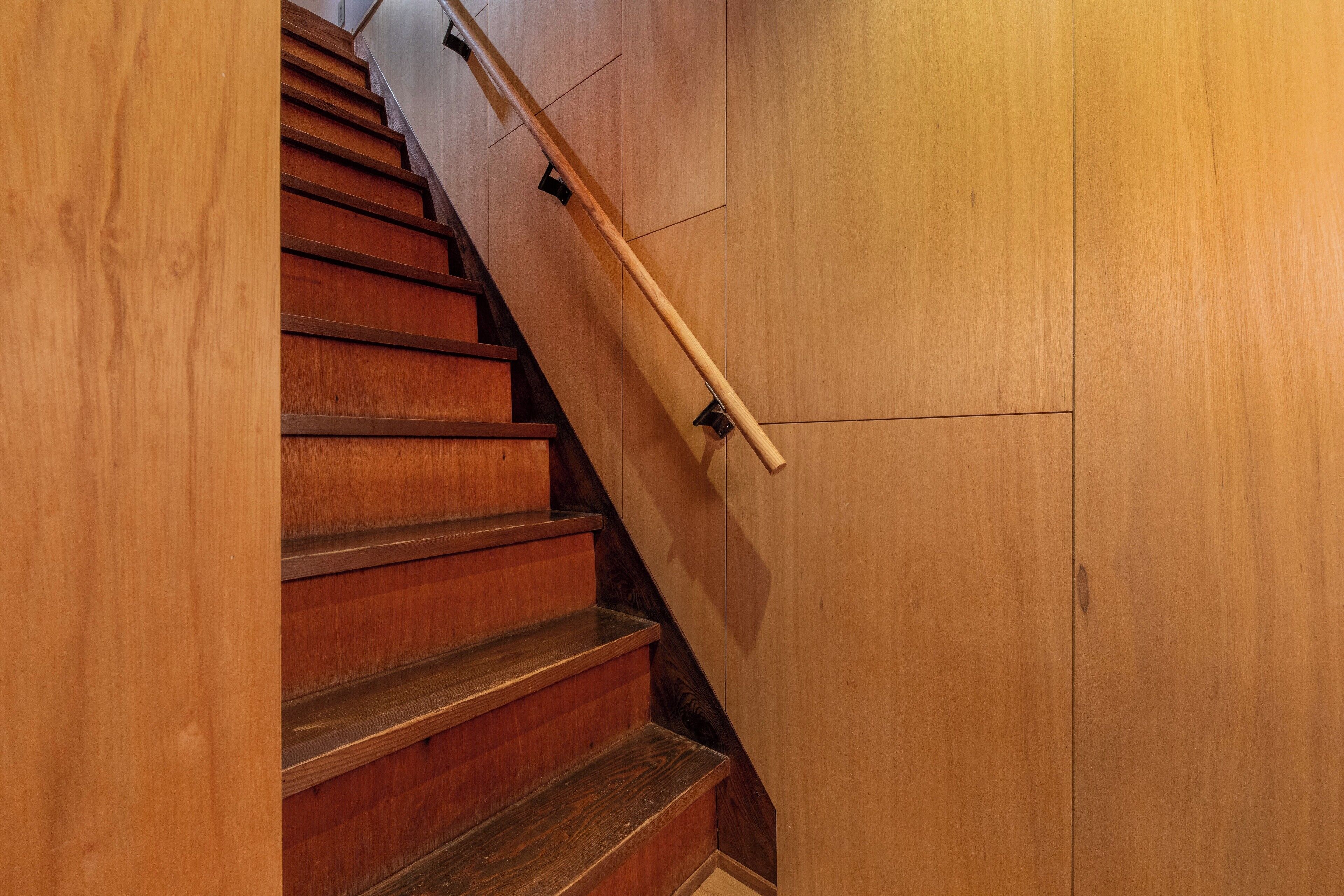 A wooden staircase with a handrail and a wooden wall.