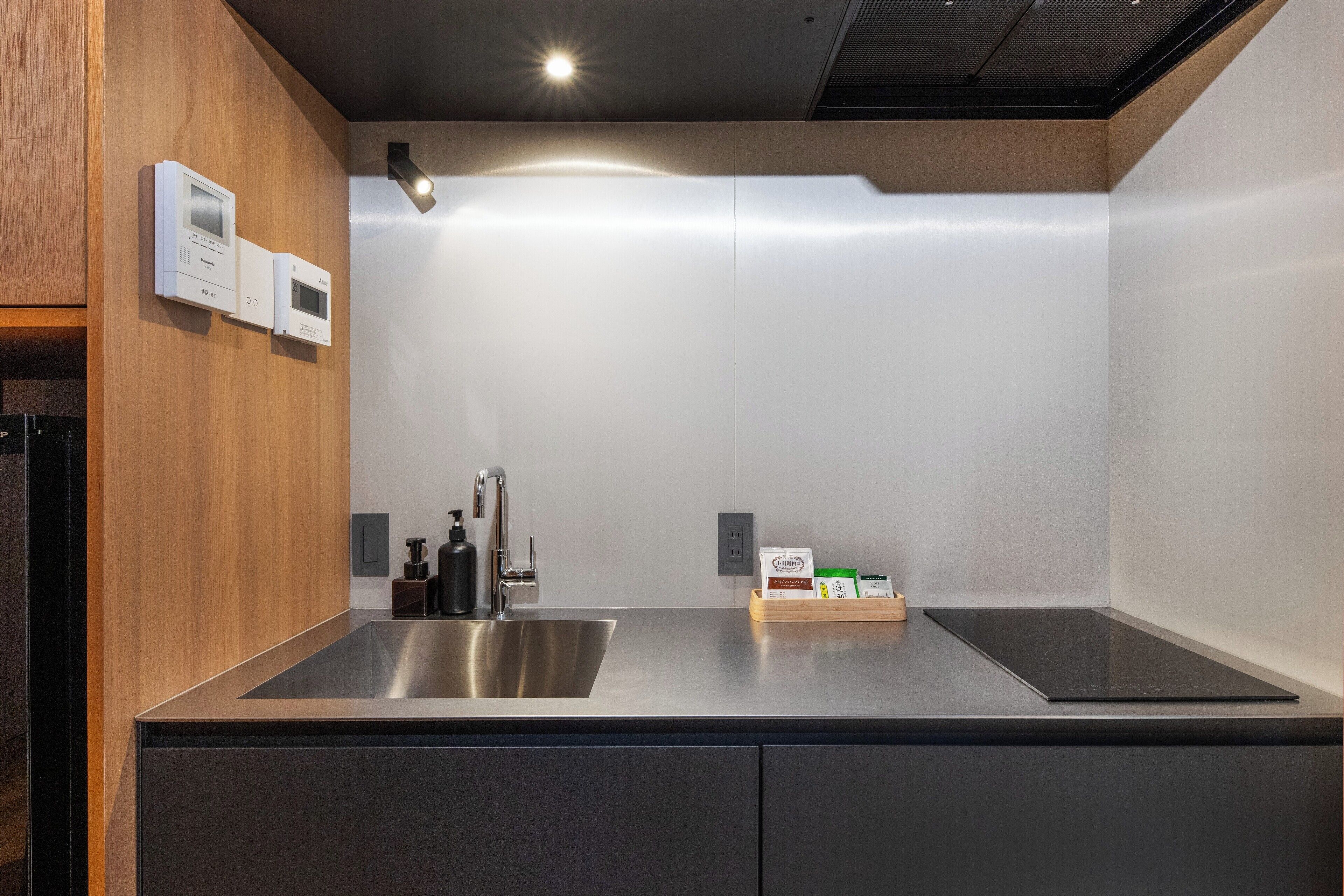 A modern kitchen with a stainless steel sink, a built-in oven, and a wooden accent wall.