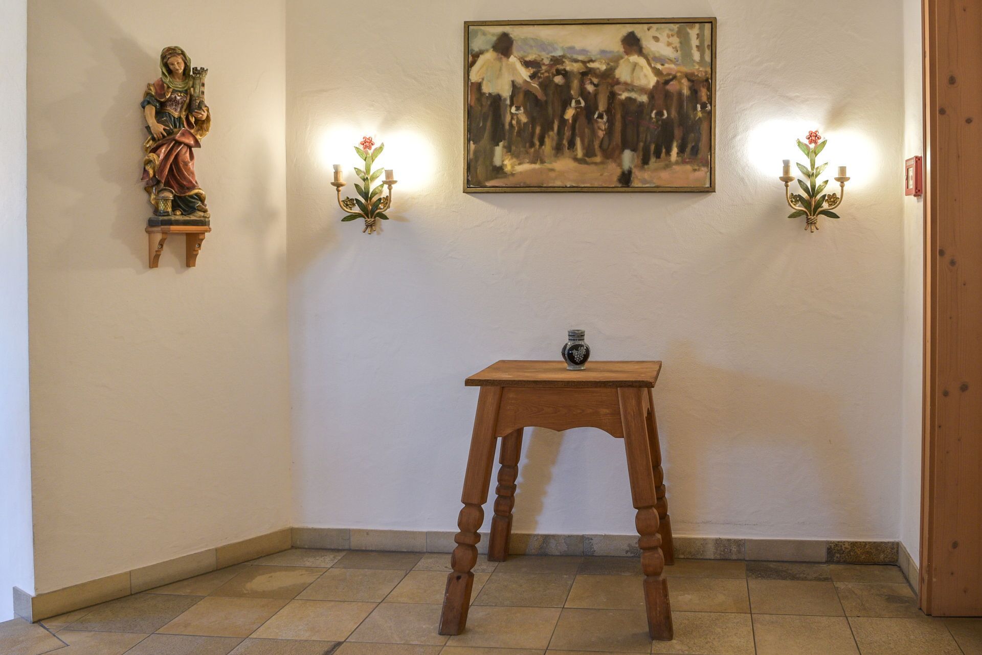 A room with a wooden table, a painting on the wall, and a statue on the left.