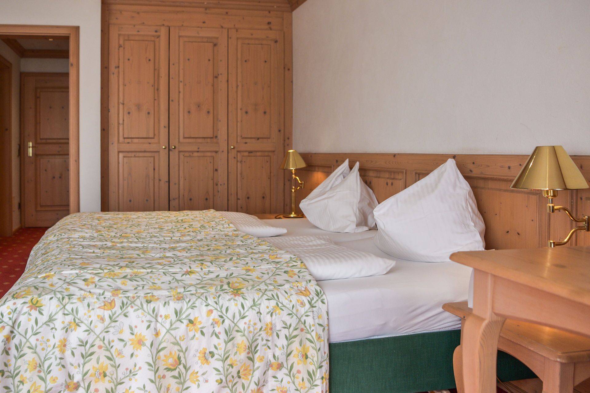 Habitación de hotel con cama, armario de madera y dos lámparas de noche.