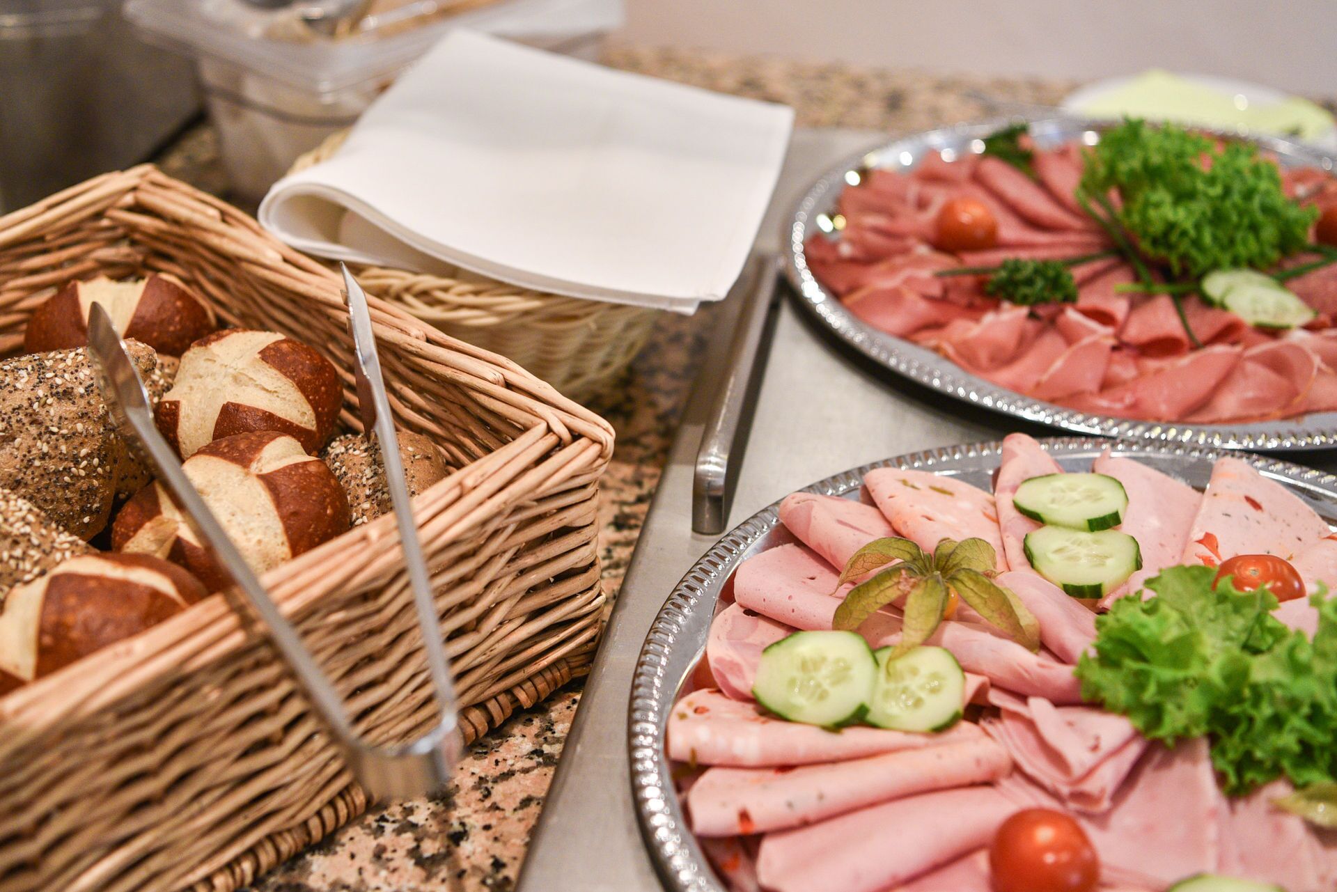A buffet with various food items including sliced meats, vegetables, and breads.