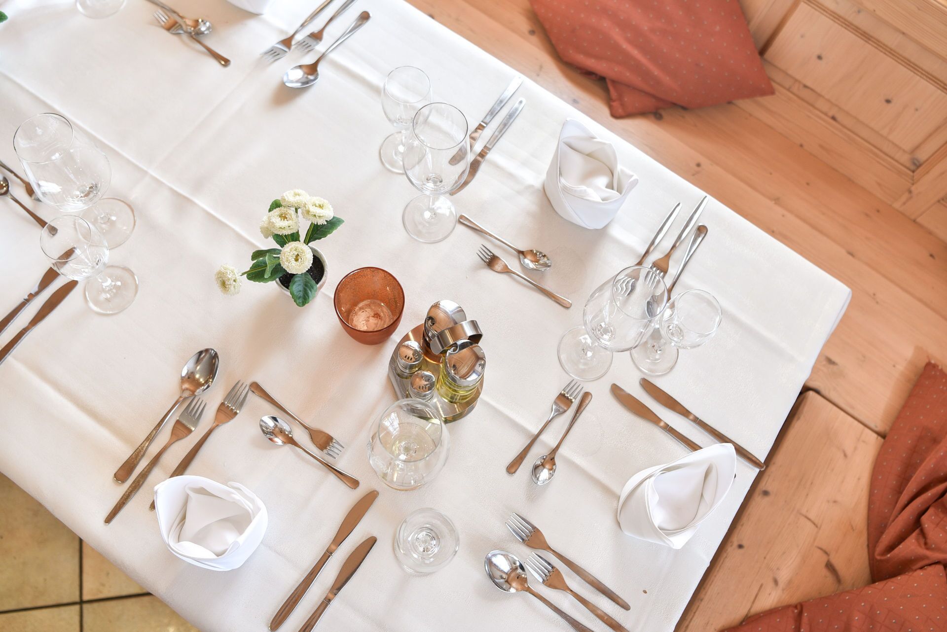 Una mesa de comedor elegantemente dispuesta con mantel blanco, cubiertos y cristalería.