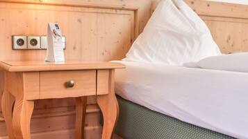 Una cama de madera con ropa de cama blanca, una mesita de noche con una lámpara y un cuadro en la pared.