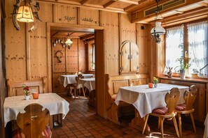 A rustic wooden interior with tables and chairs, a wooden ceiling, and a sign that reads "Jägerstuben".