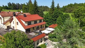 A multi-story building with a red-tiled roof, surrounded by lush greenery and trees. - Hotel Gasthof Süßer Grund (Albstadt)