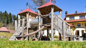 A wooden play structure with a rope slide and two red-roofed platforms. - Hotel Gasthof Süßer Grund (Albstadt)