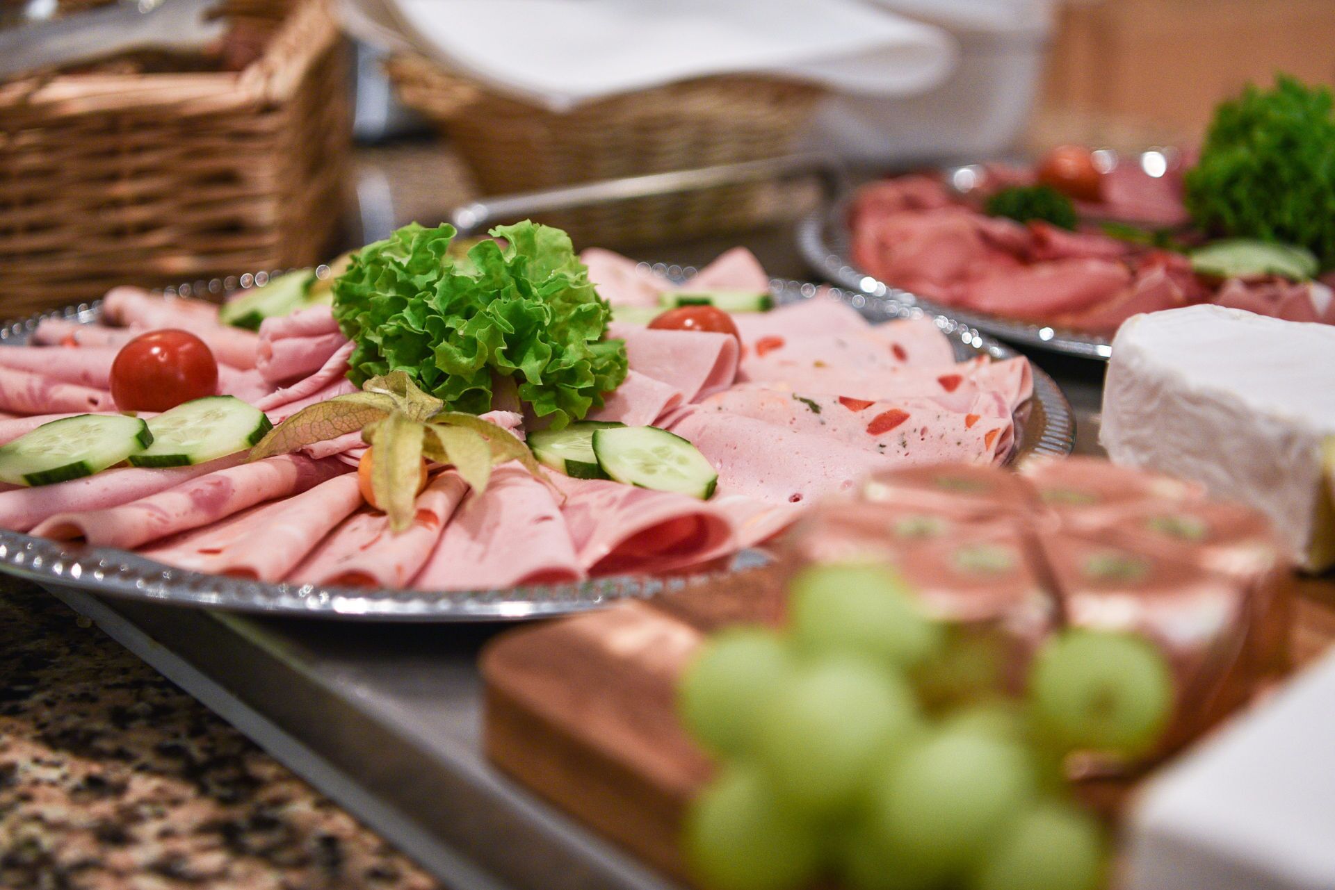 A buffet with various food items including sliced meats, vegetables, and cheese.
