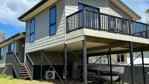 A two-story house with a covered porch and a boat parked outside. - Escape to Henry's Inlet Views, a picturesque holiday rental in the charming town of Venus Bay (Venus Bay)