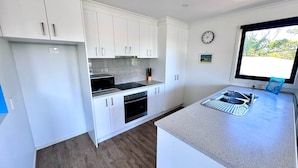 A modern kitchen with white cabinets, a stainless steel sink, and a built-in oven. - Escape to Henry's Inlet Views, a picturesque holiday rental in the charming town of Venus Bay (Venus Bay)
