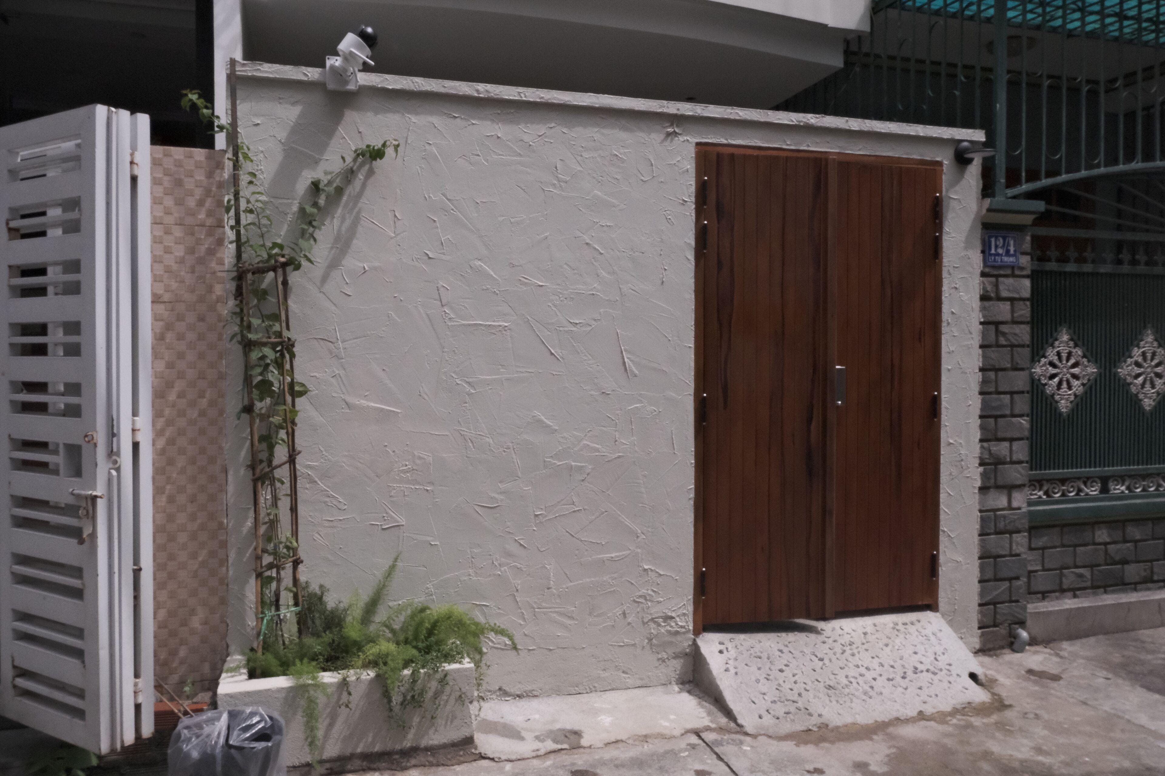 A white textured wall with a wooden door and a small porch area.