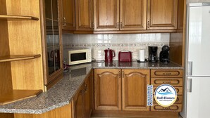 A kitchen with wooden cabinets, a microwave, a red toaster, and a coffee maker. - ID #14 BnB Homes Villa (Albufeira)