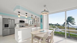 Una cucina moderna con una grande isola, elettrodomestici in acciaio inossidabile e vista su un paesaggio costiero.