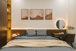 A modern bedroom with a bed, bedside table, lamp, and a wall-mounted mirror. - Tamundi Embassy - Diplomatic Quarter - West Lake Hanoi (Hanoi)