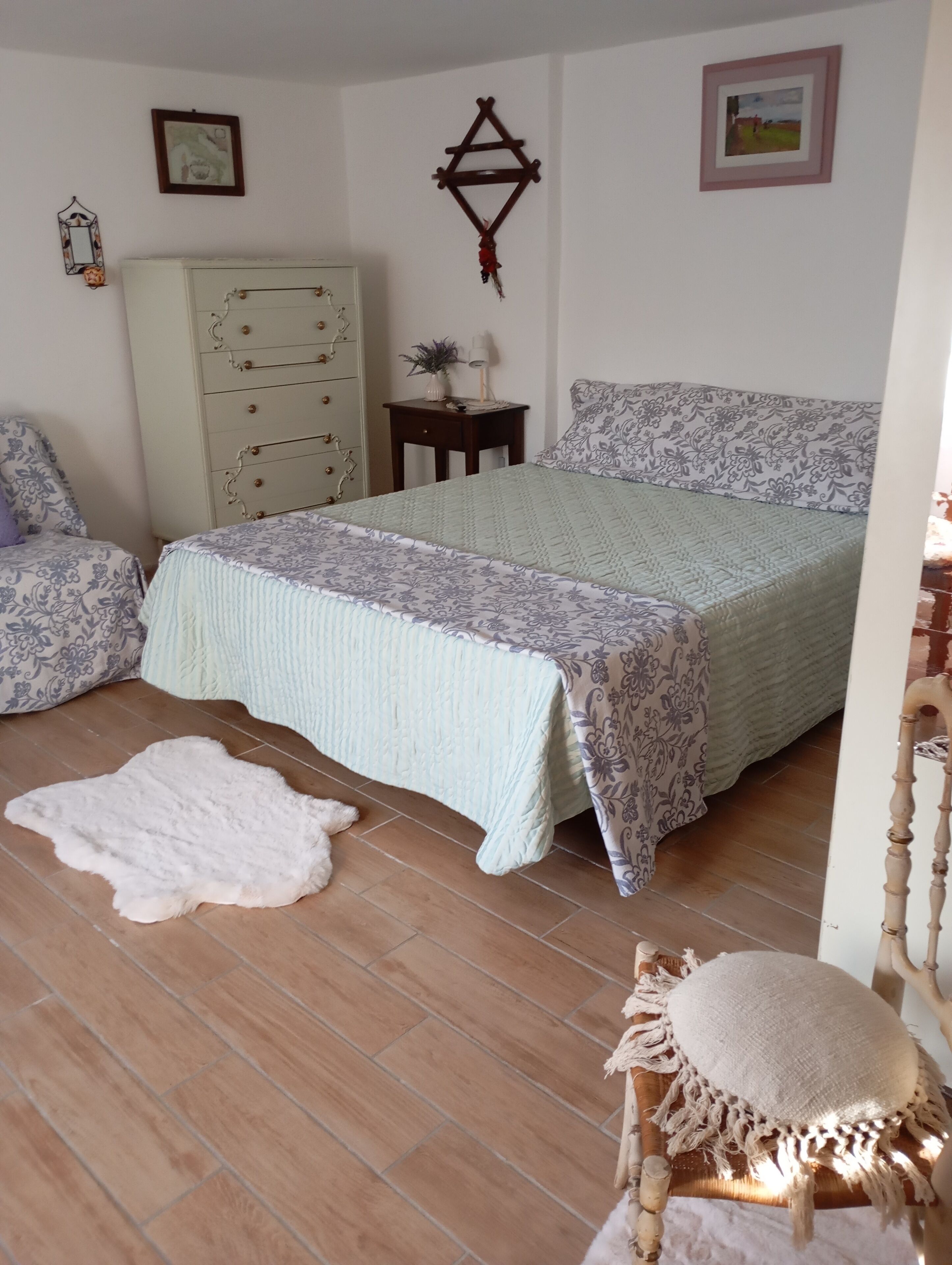 Un dormitorio con cama, cómoda, silla y alfombra.