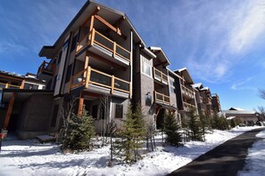 Un edificio de varios pisos con balcones, suelo cubierto de nieve y cielo despejado.