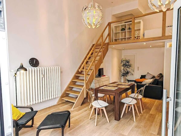 En moderne lejlighed med en trætrap, et spiseområde med bord og stole, en radiator og en sofa.